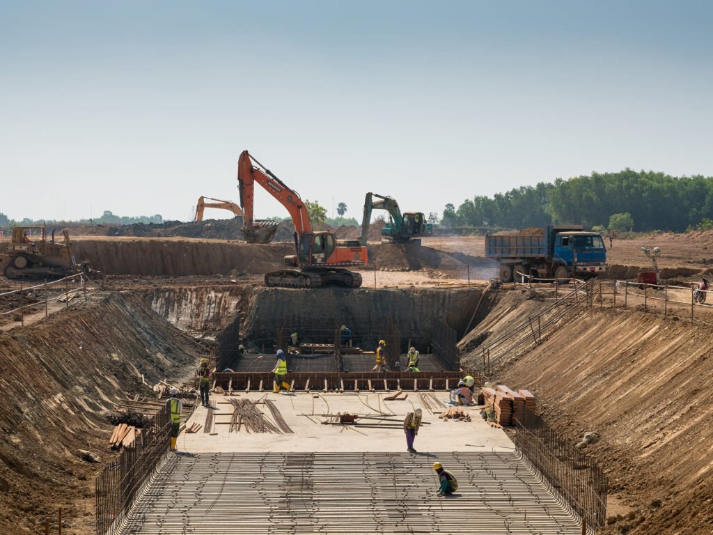 Máquinas pesadas e trabalhadores da construção civil em atividade na construção de um edifício.